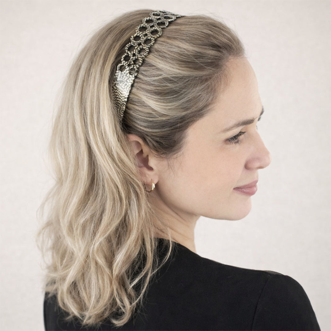 Model trägt den Haarreif Alicante im Haar, kombiniert mit einer eleganten Frisur. Der Haarreif mit doppelter Ringreihe und schimmernden Mosaikfarben setzt stilvolle Akzente und ergänzt den femininen Look perfekt.