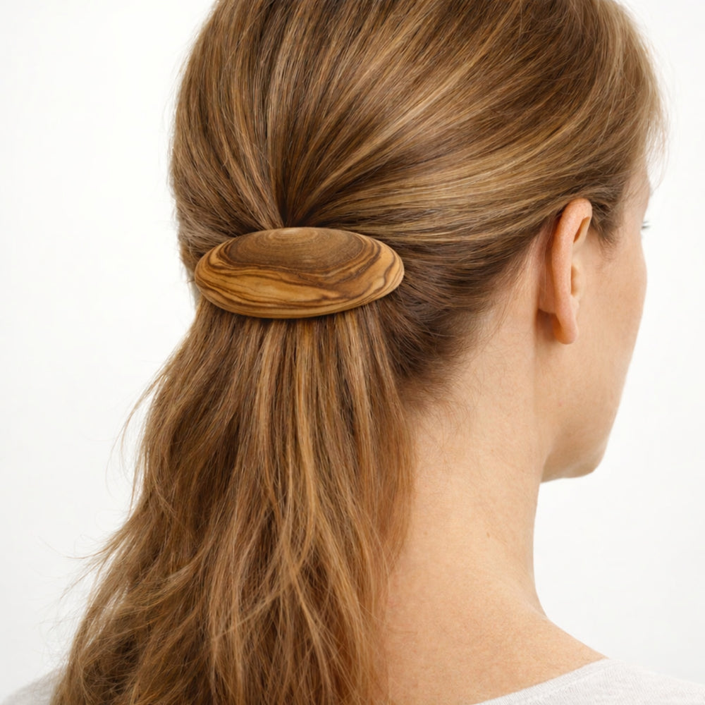 Mittelgroße Haarspange „Menor“ aus Olivenholz mit natürlicher Maserung vor hellem neutralem Hintergrund.
