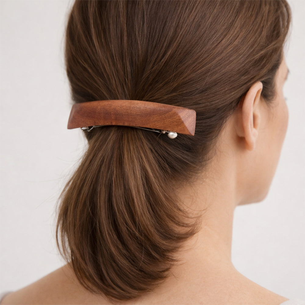 Eukalyptus-Haarspange im Haar einer Frau, Rückansicht des Kopfes mit zusammengebundenem Haar, neutraler heller Hintergrund.