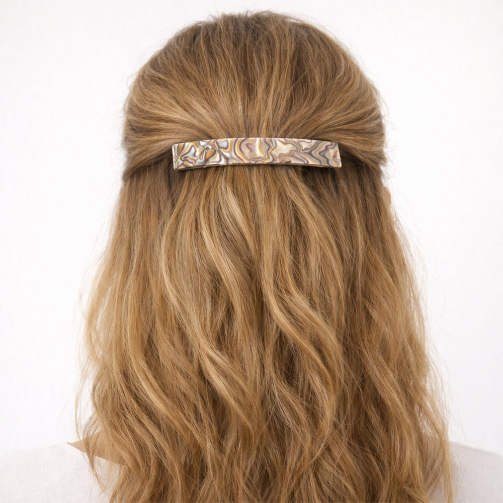 Das Model trägt eine große Haarspange mit halb offener Frisur.